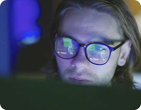 Dizüstü bilgisayarına bakan gözlüklü adam