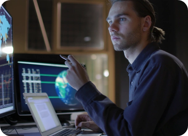 Uma imagem de um homem segurando uma caneta olhando para um monitor